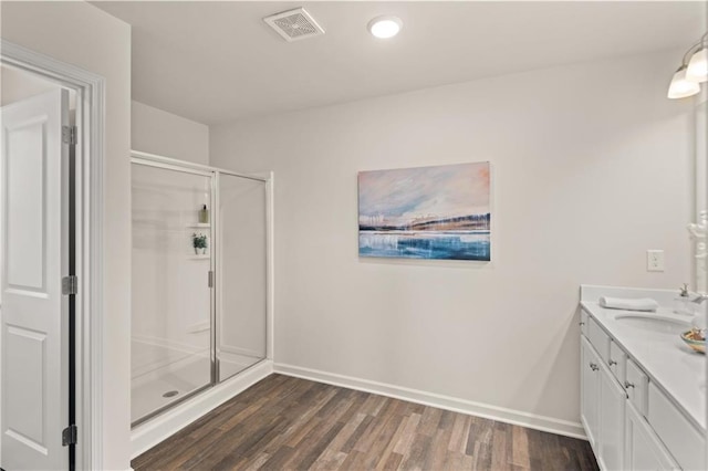 bathroom featuring wood-type flooring, a shower with shower door, and vanity