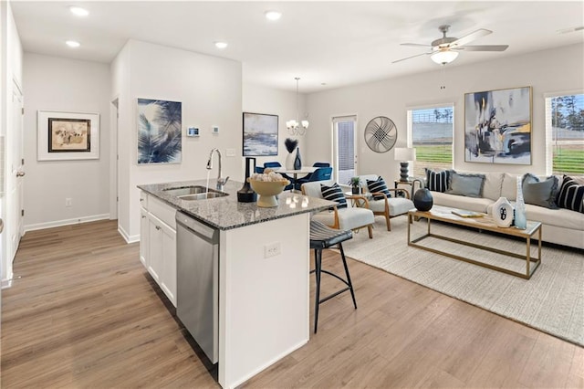 kitchen with sink, dishwasher, white cabinetry, a kitchen island with sink, and dark stone countertops