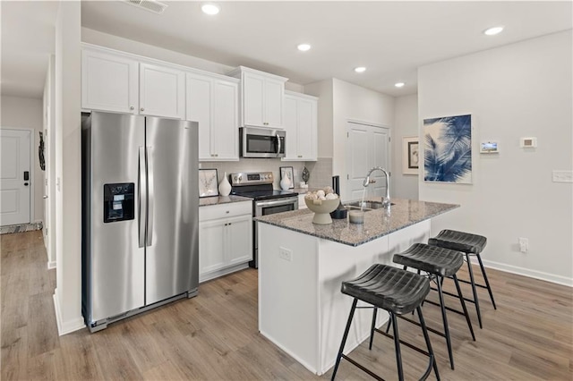 kitchen with a breakfast bar, white cabinetry, sink, a kitchen island with sink, and stainless steel appliances