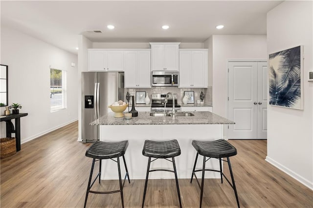 kitchen with light stone counters, sink, stainless steel appliances, and white cabinets