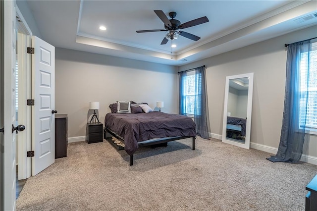 carpeted bedroom with a tray ceiling, ceiling fan, and ornamental molding