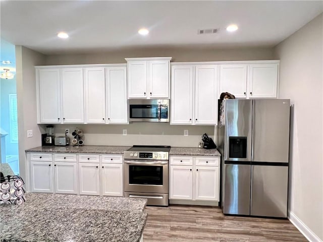 kitchen featuring light stone counters, white cabinets, light hardwood / wood-style floors, and appliances with stainless steel finishes