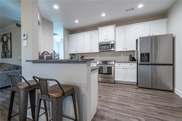 kitchen featuring kitchen peninsula, white cabinets, and stainless steel appliances