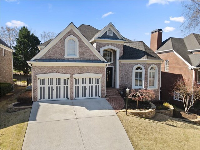 5325 Davenport Mnr, Cumming, GA 30041 - view of front of house featuring a garage, a standing seam roof, brick siding, and concrete driveway