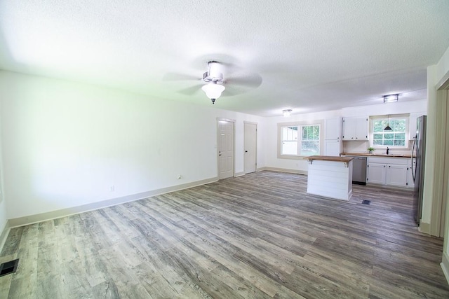 178 Wayne St SW, Calhoun, GA 30701 - unfurnished living room featuring wood finished floors, baseboards, a textured ceiling, ceiling fan, and a sink