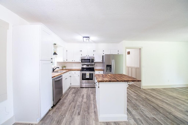 178 Wayne St SW, Calhoun, GA 30701 - kitchen with appliances with stainless steel finishes, butcher block countertops, light wood-style floors, a kitchen island, and white cabinetry