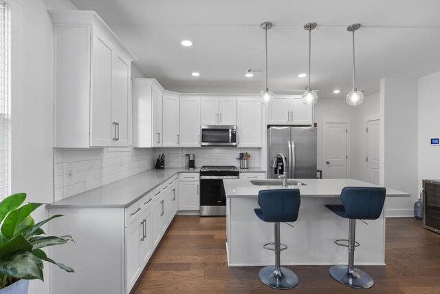 kitchen with backsplash, dark wood finished floors, light countertops, stainless steel appliances, and white cabinetry