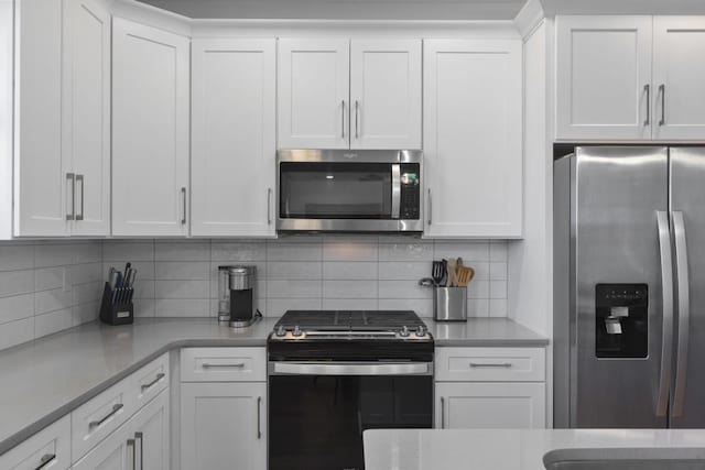 kitchen with white cabinetry, backsplash, and stainless steel appliances