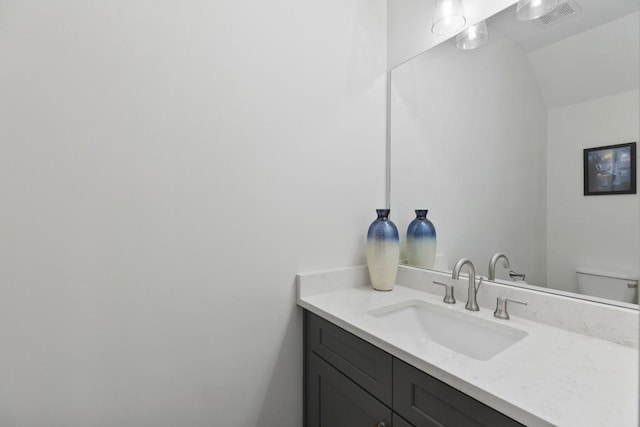 bathroom with vanity, toilet, and visible vents