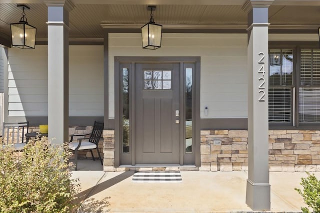 view of exterior entry featuring covered porch and stone siding