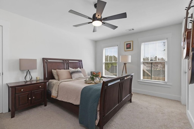 bedroom featuring visible vents, light colored carpet, baseboards, and ceiling fan