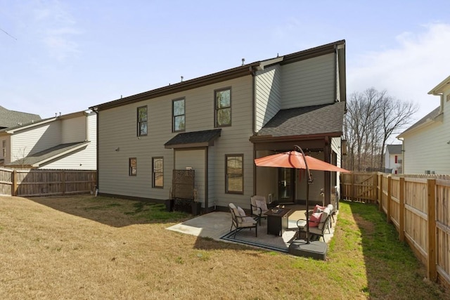 back of house with a shingled roof, a lawn, a fenced backyard, and a patio area