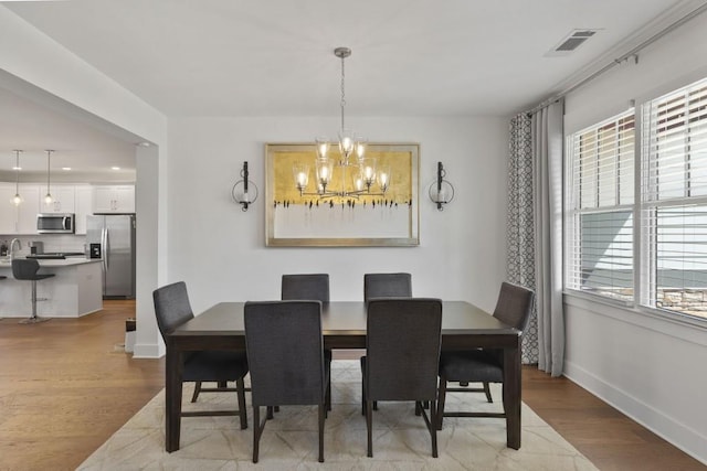 dining room with visible vents, baseboards, a chandelier, and light wood finished floors