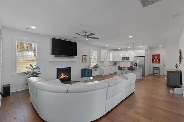 living area with visible vents, wood finished floors, recessed lighting, a fireplace, and baseboards