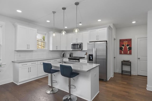 kitchen with a sink, appliances with stainless steel finishes, white cabinets, and dark wood-style flooring