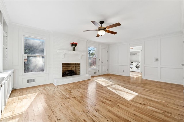 unfurnished living room featuring ceiling fan, a fireplace, washer and dryer, and light hardwood / wood-style flooring