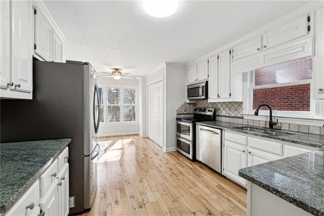 kitchen featuring tasteful backsplash, white cabinetry, ceiling fan, and stainless steel refrigerator