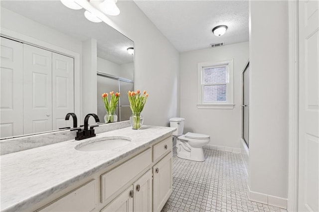 full bathroom with tile patterned floors, toilet, bath / shower combo with glass door, a textured ceiling, and vanity