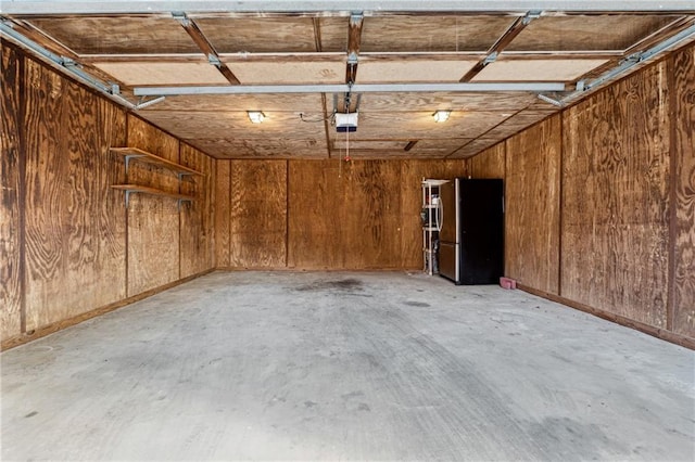 garage with a garage door opener and stainless steel fridge