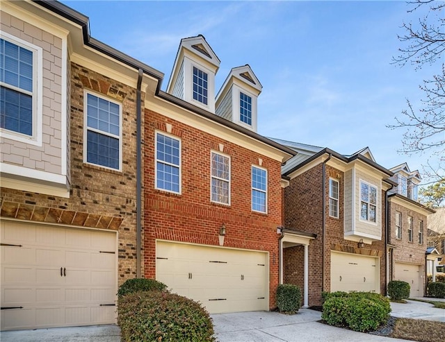 townhome / multi-family property featuring a garage, brick siding, and driveway