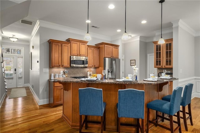 kitchen with appliances with stainless steel finishes, brown cabinets, visible vents, and wood finished floors