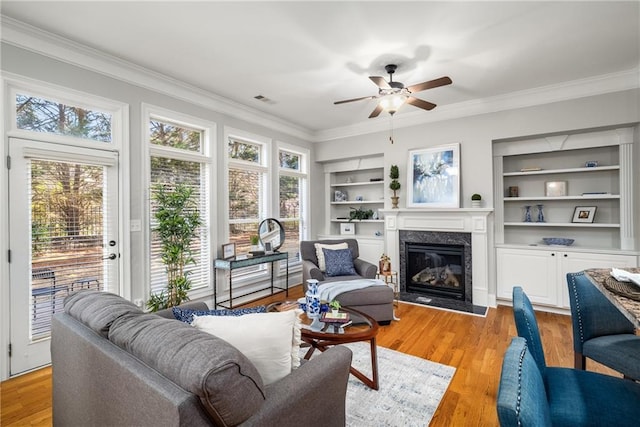 living area with light wood-type flooring, plenty of natural light, built in features, and crown molding