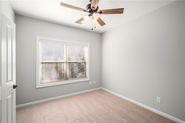 carpeted spare room with a ceiling fan and baseboards