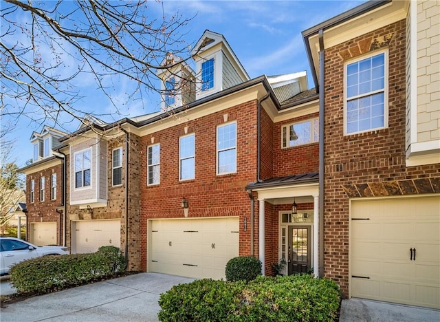 townhome / multi-family property with concrete driveway, brick siding, and an attached garage