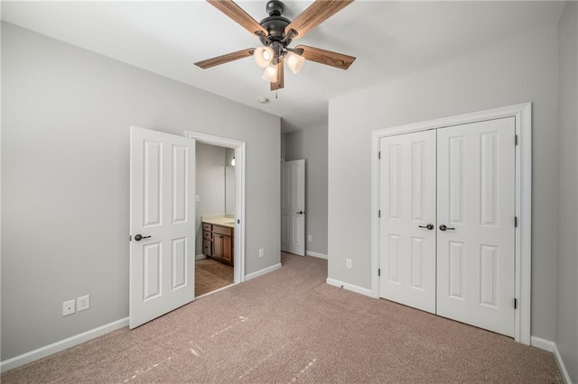 unfurnished bedroom with a closet, light colored carpet, ceiling fan, ensuite bath, and baseboards