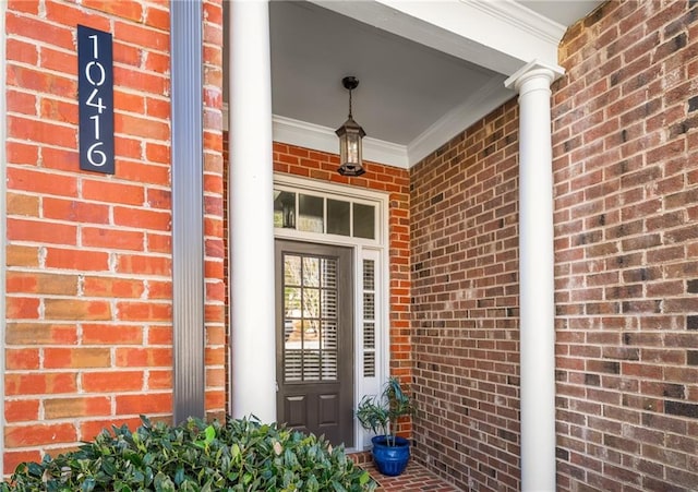 view of exterior entry with covered porch and brick siding