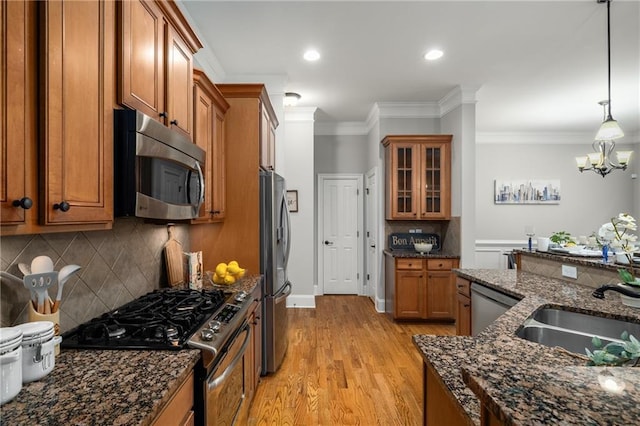 kitchen featuring light wood-style flooring, ornamental molding, brown cabinets, glass insert cabinets, and stainless steel appliances