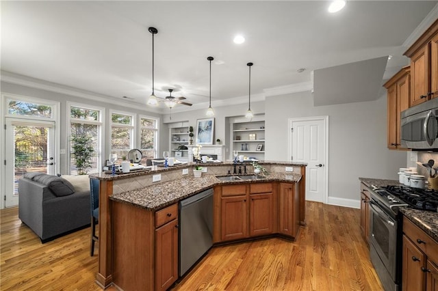 kitchen featuring crown molding, light wood finished floors, appliances with stainless steel finishes, brown cabinetry, and open floor plan