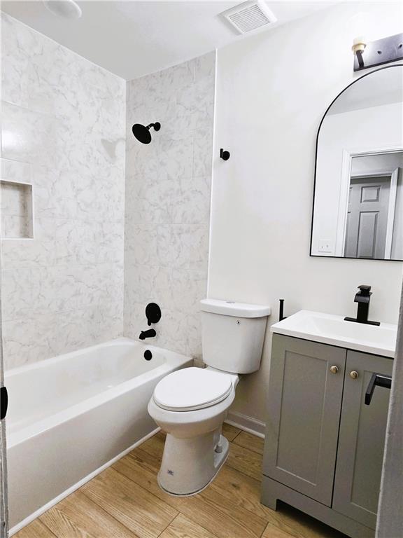 bathroom with washtub / shower combination, visible vents, toilet, and wood finished floors