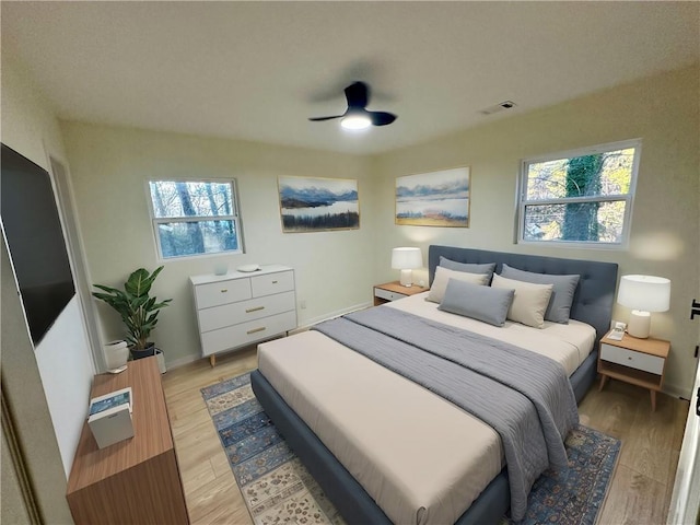 bedroom featuring a ceiling fan, light wood-type flooring, visible vents, and baseboards