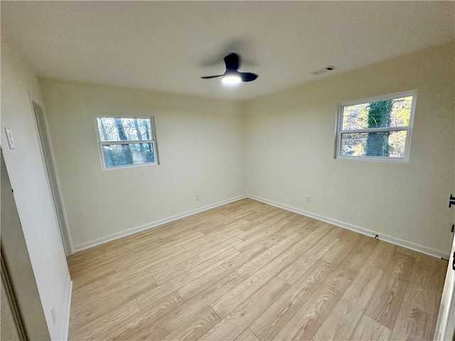 spare room featuring light wood-style flooring, visible vents, baseboards, and ceiling fan