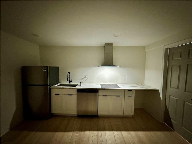 kitchen with dark wood finished floors, light countertops, appliances with stainless steel finishes, a sink, and wall chimney range hood