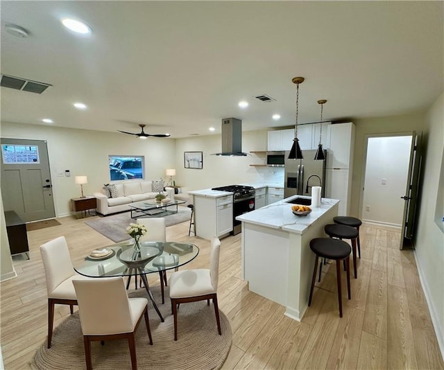 kitchen with light wood-type flooring, range hood, visible vents, and appliances with stainless steel finishes