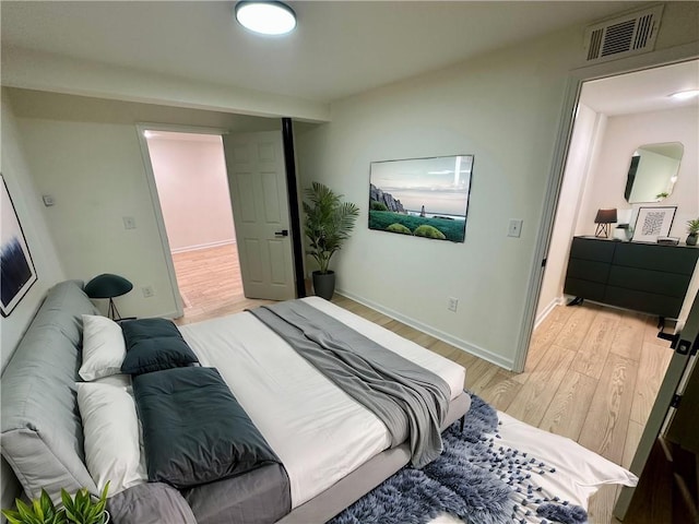 bedroom featuring light wood-type flooring, visible vents, and baseboards