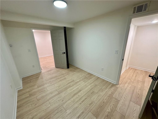 spare room with baseboards, visible vents, and light wood finished floors