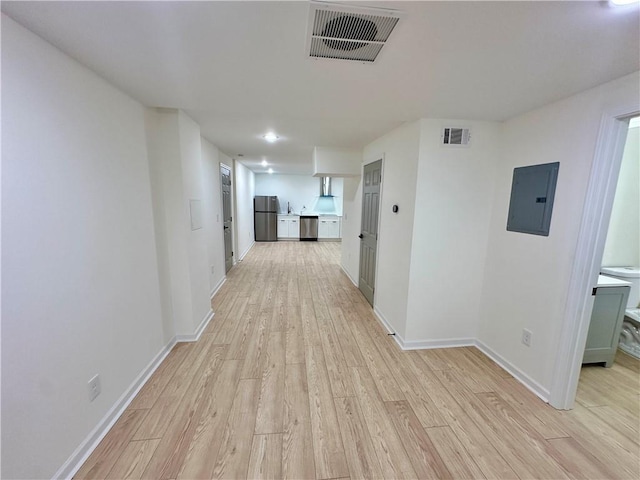 corridor featuring light wood-type flooring, baseboards, electric panel, and visible vents