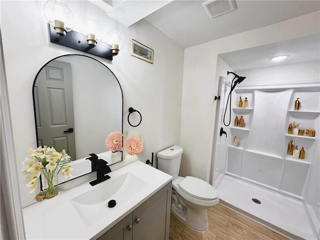 bathroom with toilet, wood finished floors, vanity, visible vents, and a shower stall