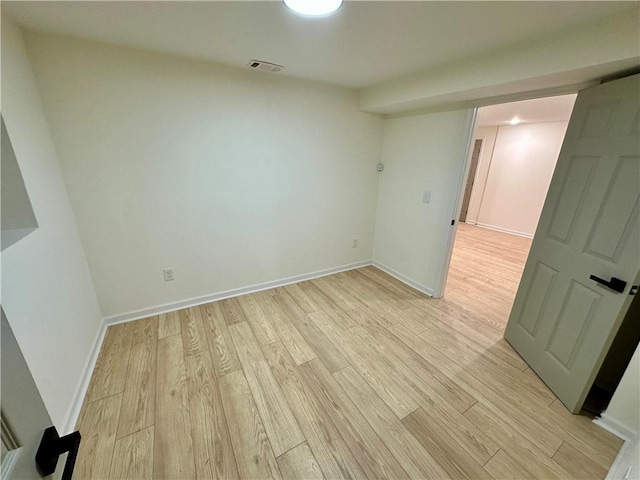 spare room with baseboards, visible vents, and light wood finished floors