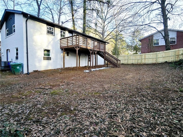 back of property featuring stairs, fence, a deck, and brick siding