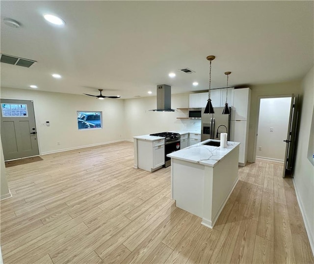 kitchen with stainless steel appliances, range hood, visible vents, and light wood finished floors