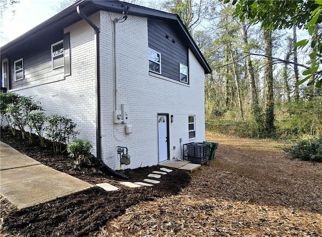 view of property exterior with brick siding and central air condition unit