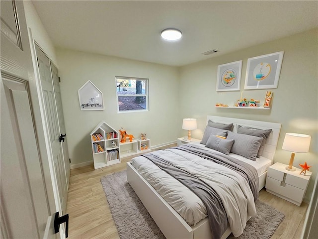 bedroom featuring light wood finished floors, visible vents, and baseboards