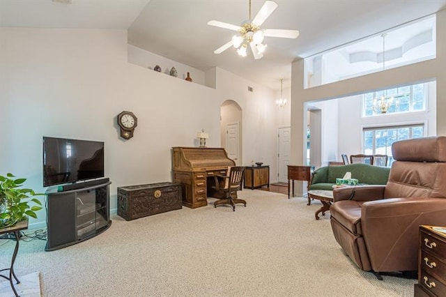 interior space with ceiling fan with notable chandelier, light colored carpet, and high vaulted ceiling