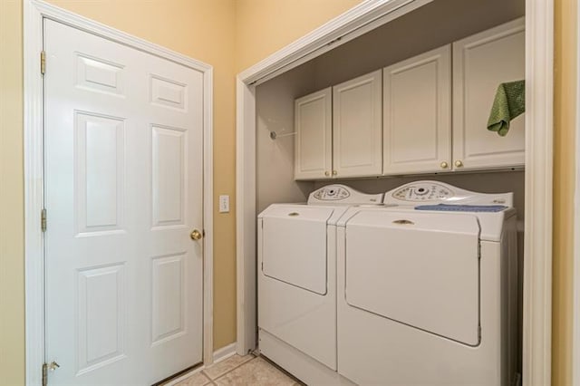 washroom featuring cabinets, washing machine and dryer, and light tile patterned floors