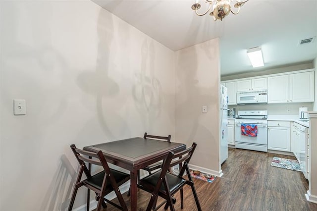 dining space with dark hardwood / wood-style floors and a notable chandelier