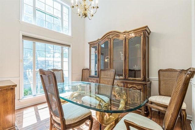 dining area with a towering ceiling, light hardwood / wood-style flooring, and a chandelier